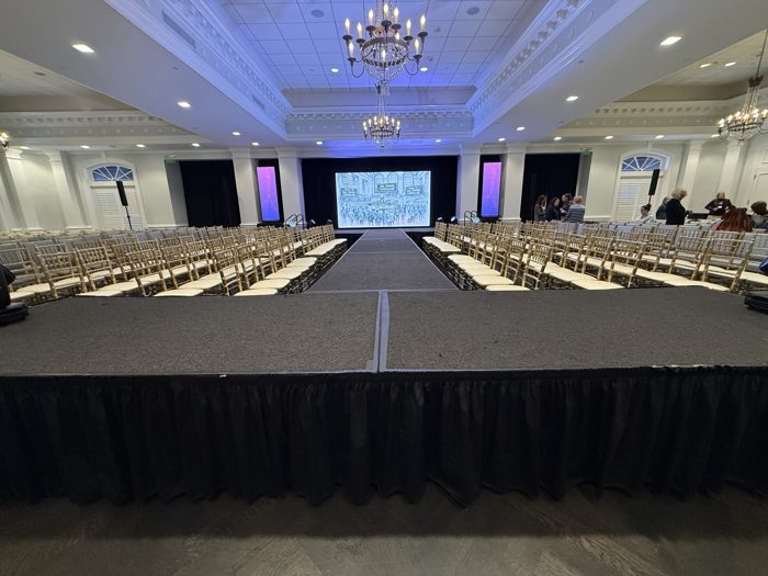 Formal event aisle with gold chiavari chairs and stage screen