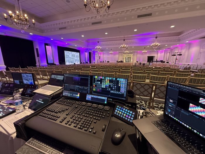 Full production console overlooking a large ballroom keynote