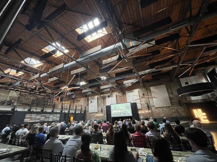 Seated crowd at a corporate presentation in a brick venue