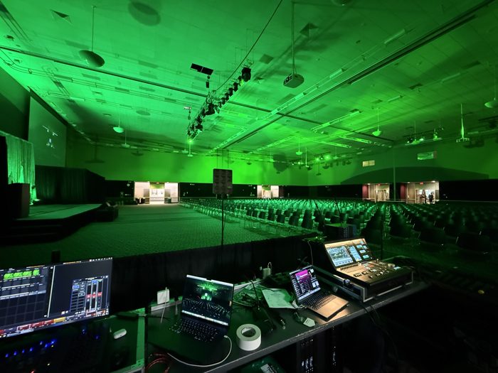 Large ballroom lit in green with rows of seating