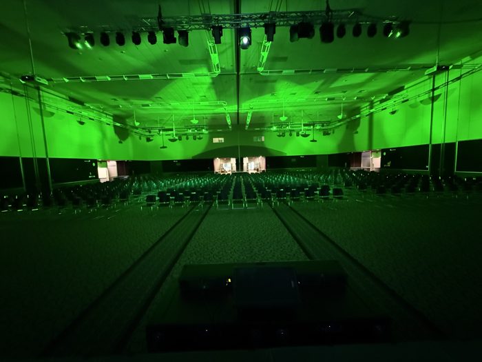 Ballroom lit in green, wide view of seating